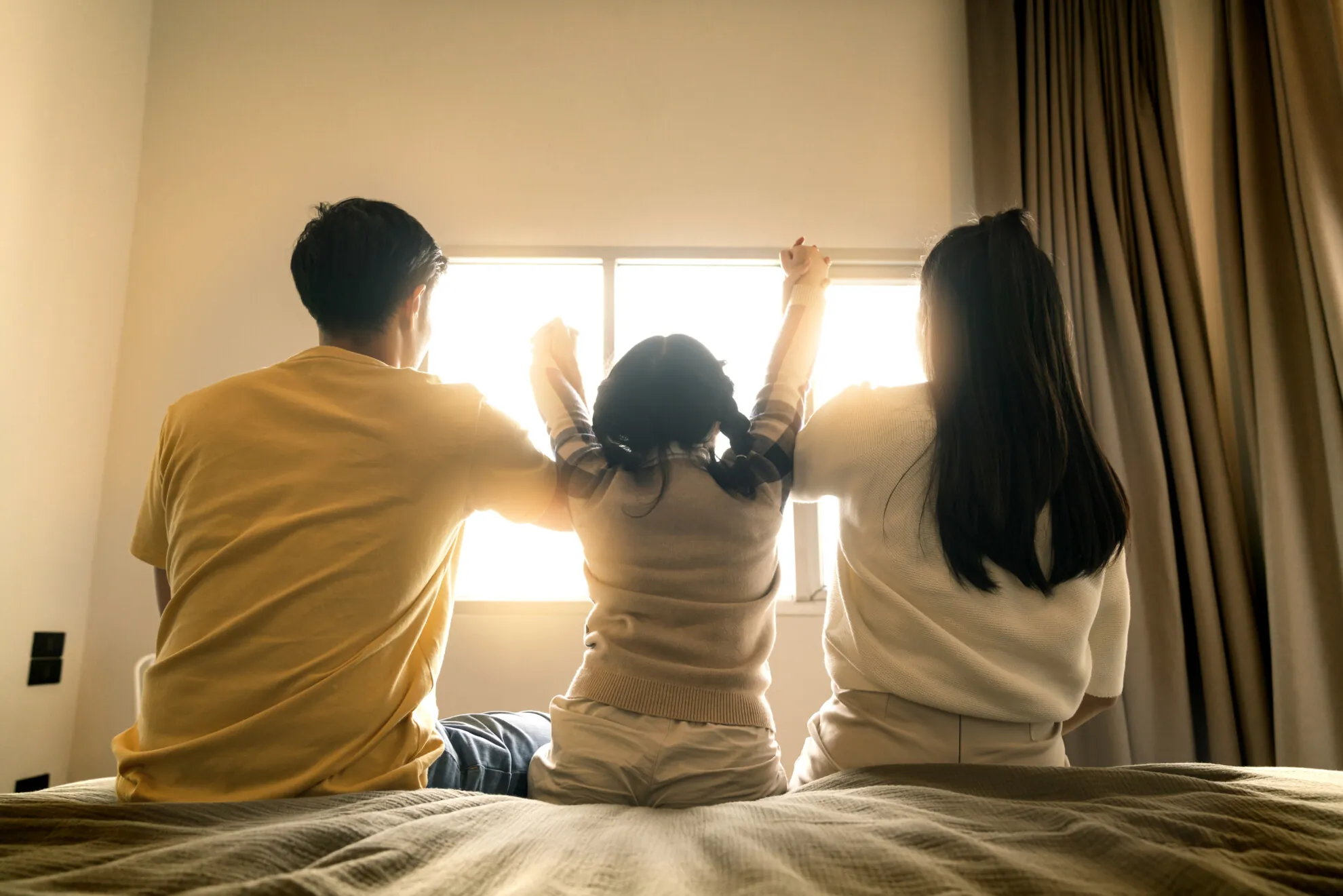 Together forever love asian family hand together with morning sunlight flare from window bed mom dad daighter hand hold together with care love bedroom